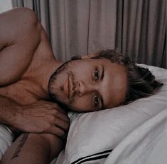 a shirtless man laying on top of a bed