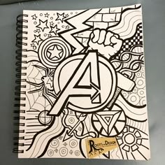 a spiral notebook with the letter a on it and doodled artwork in black and white