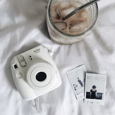 a polaroid camera sitting on top of a bed next to some polaroid pictures