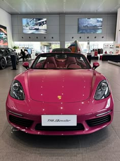 a pink sports car parked in a showroom