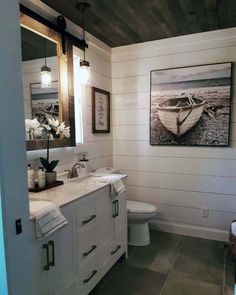 a bathroom with two sinks, a toilet and a painting on the wall above it