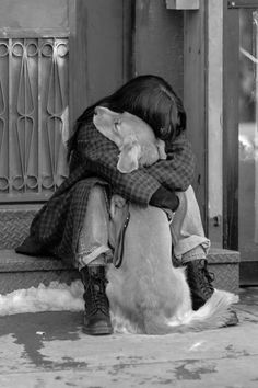 black and white photograph of a person hugging a dog on the front steps of a building