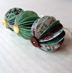 four green and white paper flowers with brown buttons on each flower, sitting on a table