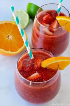 two glasses with strawberries, oranges and lime on the side next to each other