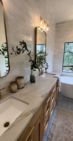 a bathroom with two sinks, a tub and a large window in the back ground