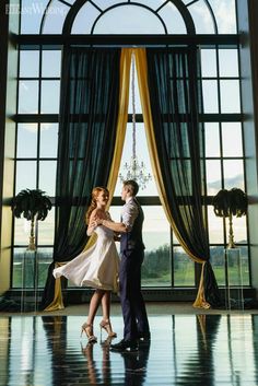 a man and woman standing in front of a window with their arms around each other