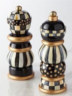 two black and white striped salt and pepper shakers on a marble counter top with gold accents