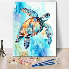 a watercolor painting of a sea turtle on a canvas next to some pencils