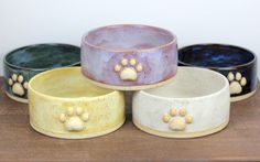 four dog bowls with paw prints on them sitting on a table next to each other