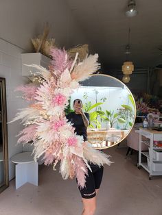 a woman is taking a selfie in front of a mirror with feathers on it