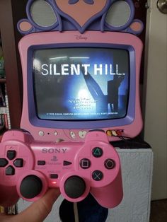 a person holding a pink video game controller in front of a tv with the words silent hill on it