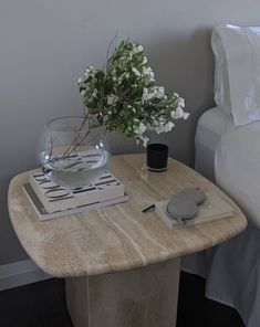 a table with a vase and some flowers on it next to a bed in a room