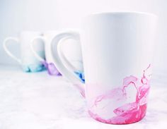 three white coffee mugs with pink, blue and purple swirled designs on the inside