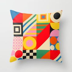 a colorful pillow with an abstract design on the front and back side, sitting against a white wall