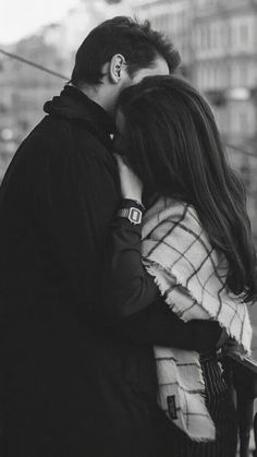 black and white photograph of a couple kissing on a balcony overlooking an urban city street