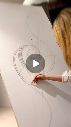 a woman is drawing on a large piece of paper