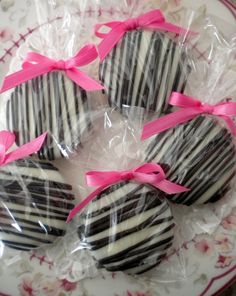 four chocolates wrapped in cellophane and tied with pink ribbon on a plate