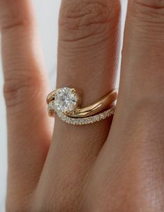 a woman's hand with a diamond ring on top of her finger and an engagement band