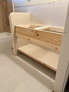 an unfinished wooden bench in a bathroom with white tile flooring and walls behind it