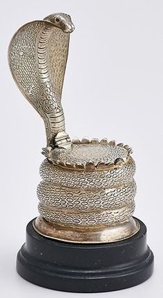 a silver snake statue sitting on top of a black base