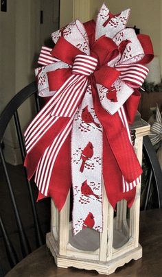 a red and white christmas bow sitting on top of a wooden table next to a chair