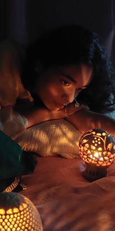 a woman laying in bed next to a lit candle