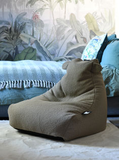 a brown bean bag sitting on top of a bed next to a blue comforter