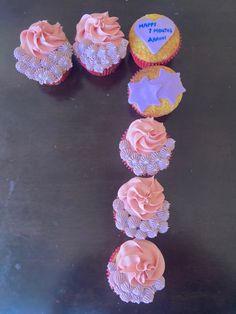 several cupcakes with pink frosting and purple icing on a black surface