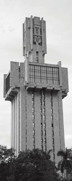 a very tall building with a clock on it's side and trees in the foreground