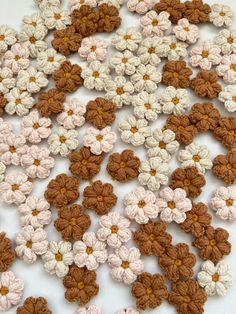 crocheted flowers are arranged on a white tablecloth with brown and tan centers