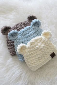 two crocheted hats laying on top of white fur