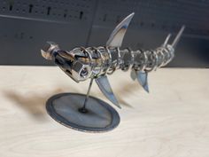 a metal fish sculpture sitting on top of a wooden table