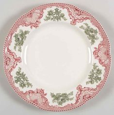 a pink and white plate with green designs on it's rim, against a gray background