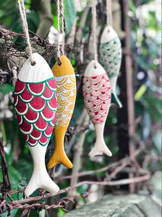 three colorful fish ornaments hanging from a tree