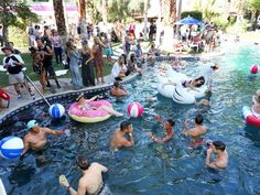 many people are playing in the pool with floats and water toys while others look on