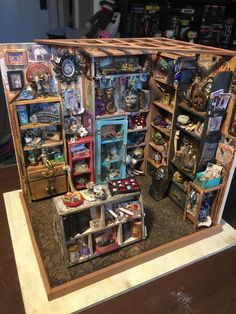 a display case filled with assorted items on top of a wooden table next to a book shelf