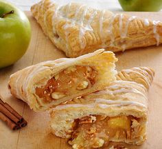 an apple pie is cut in half on a cutting board next to cinnamon sticks and apples