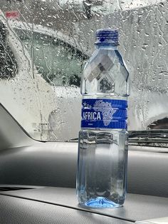 a bottle of water sitting on the dashboard of a car in front of a window