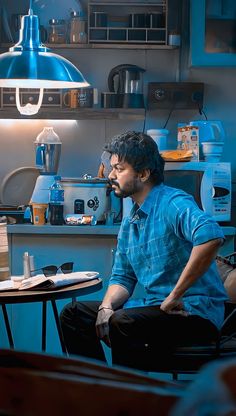 a man sitting at a table in front of a blue light with his hands on his hips