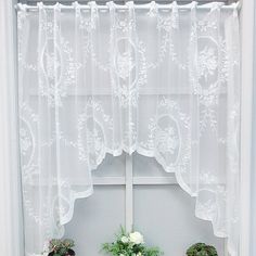 two potted plants sit on a window sill in front of a white curtain