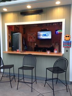 three chairs sitting in front of a bar with a tv on the wall behind it