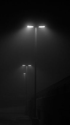 three street lights in the dark on a foggy night