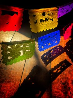 colorful paper cutouts on a wooden table with shadows from the light coming through them