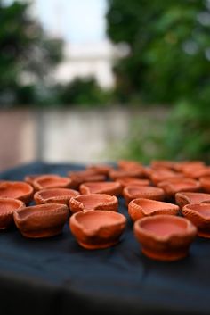 several clay pots are lined up on a table outside in front of some trees and bushes