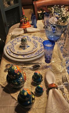 the table is set with blue and white dishes, silverware, and other decorative items