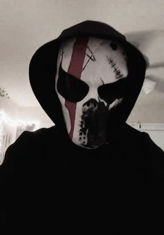 a person in a black hoodie wearing a white mask with red lines on it