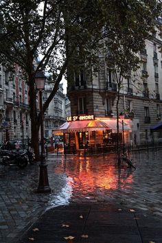 a rainy day in the city with people walking down the street and umbrellas on the sidewalk