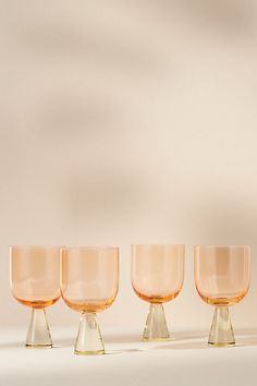 three glasses sitting next to each other on top of a white tablecloth covered floor