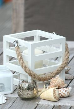 some seashells are sitting on a table next to a white container with rope