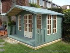 a small blue shed sitting on top of a lush green field